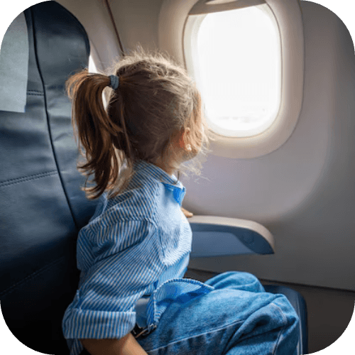 Child gazing out the window of an airplane mid-flight